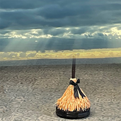 big picture of a broom on a vacuum with a bright sky and clouds in the background.