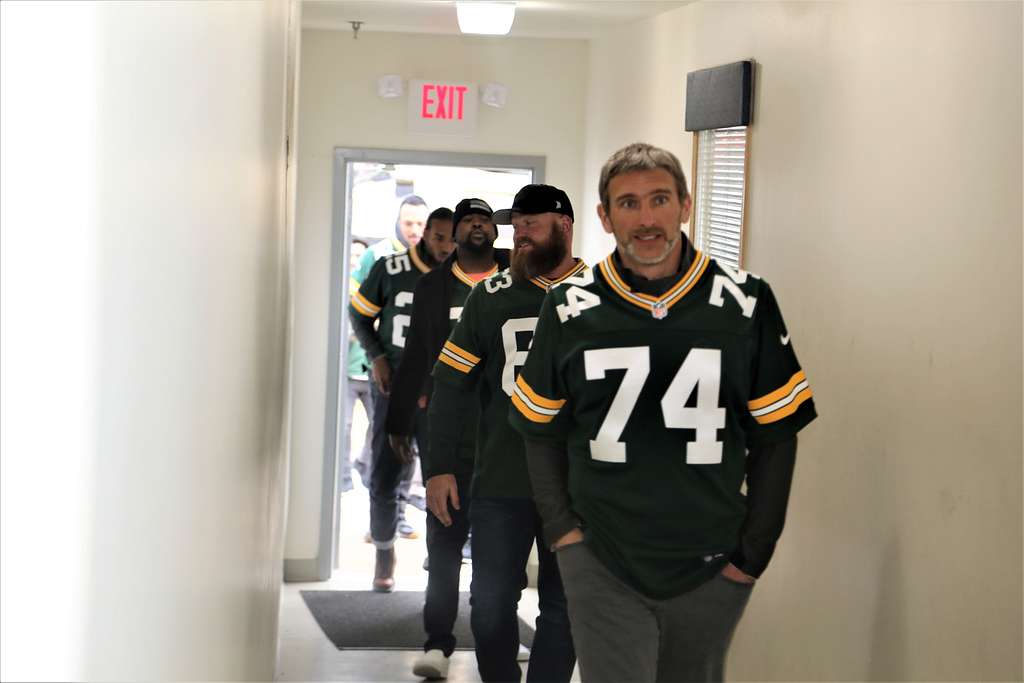 People with Green, Yellow, and white jerseys walking into a room.