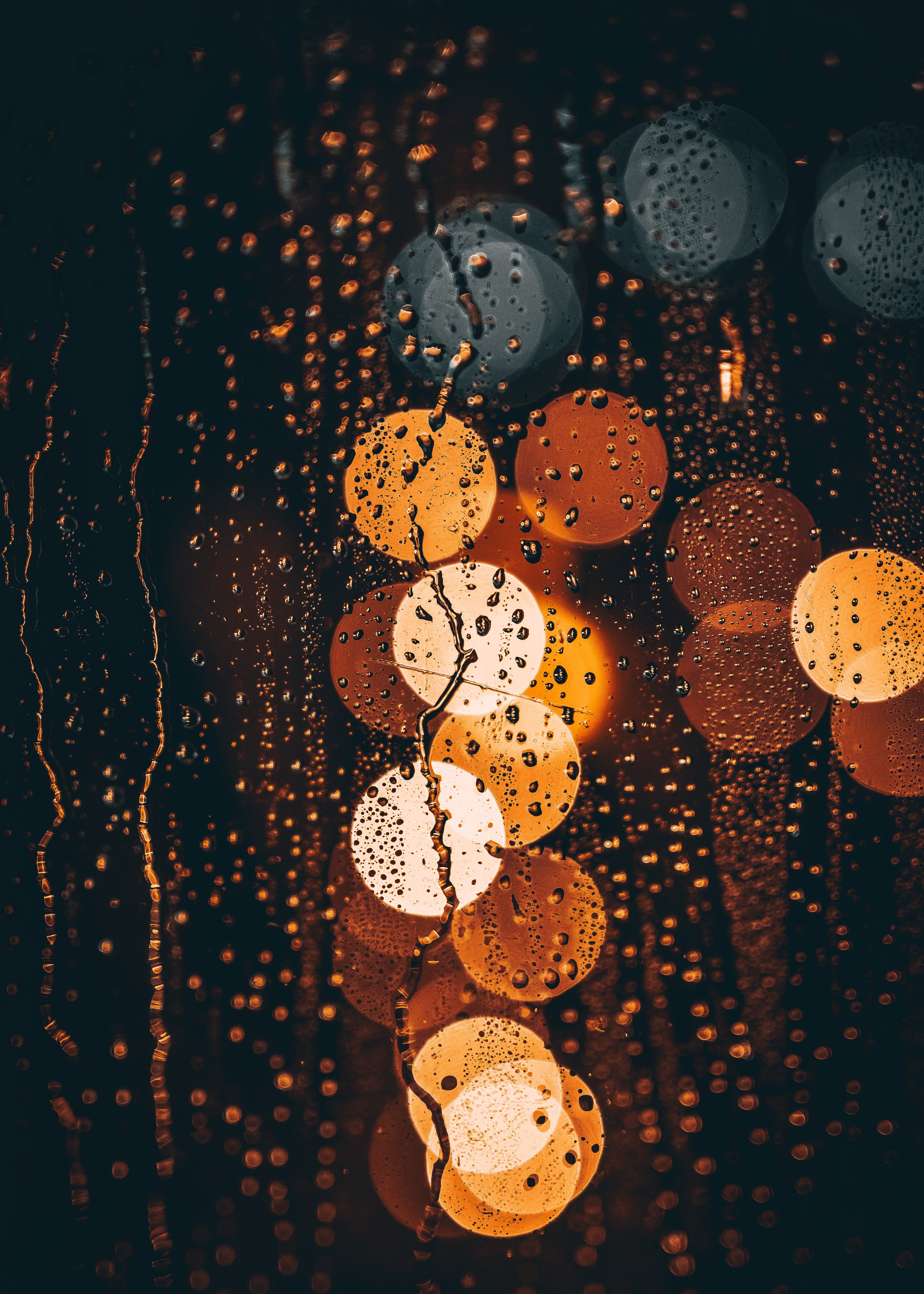 A window with rain falling on it and blurred lights in the background